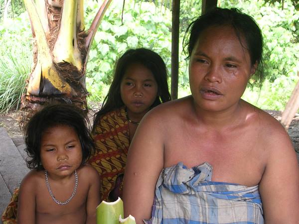 Mother with two children beneath a stilt house in jungle