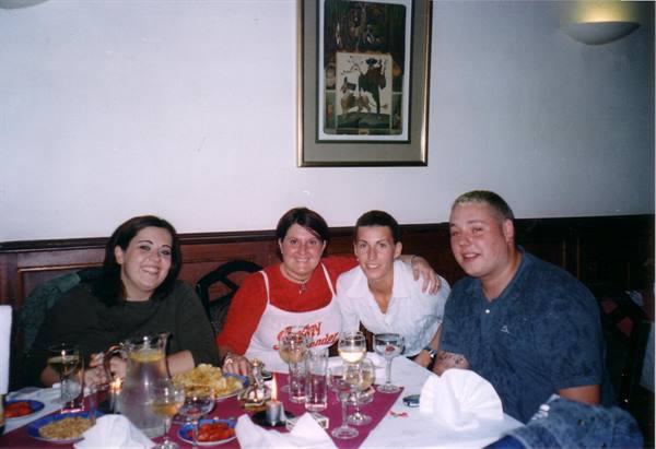 Four smiling friends at a restaurant table with glasses and plates