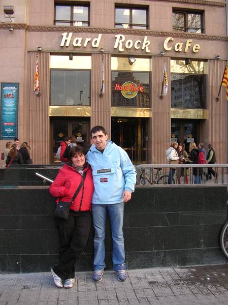 Couple in red and blue jackets outside Hard Rock Cafe, lights on