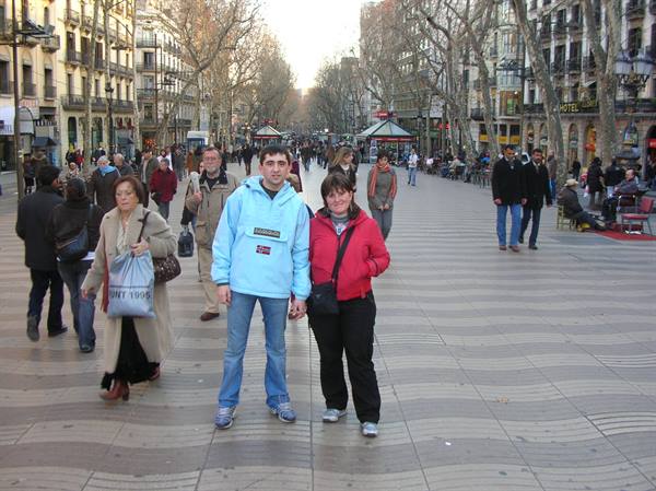 Couple standing on Barcelona's Rambla, wavy pavement, bare trees and passersby