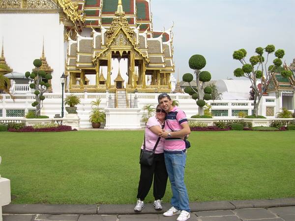 Couple hugging in front of the golden pavilion at Bangkok's Grand Palace