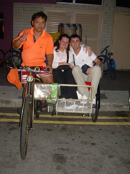 Tourists on a pedicab with driver, city street at night