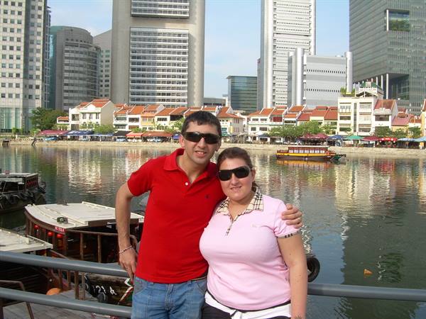 Couple in sunglasses at Boat Quay riverside, Singapore, among boats and skyscrapers