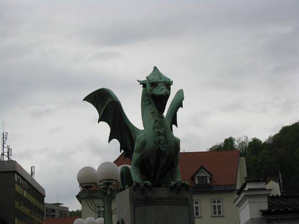 Green bronze dragon statue on Ljubljana's Dragon Bridge under overcast sky