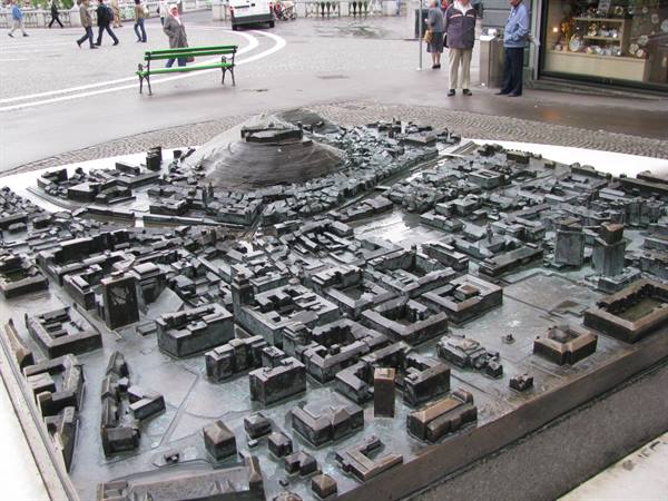 Bronze city model with fortress, tourists standing around the square