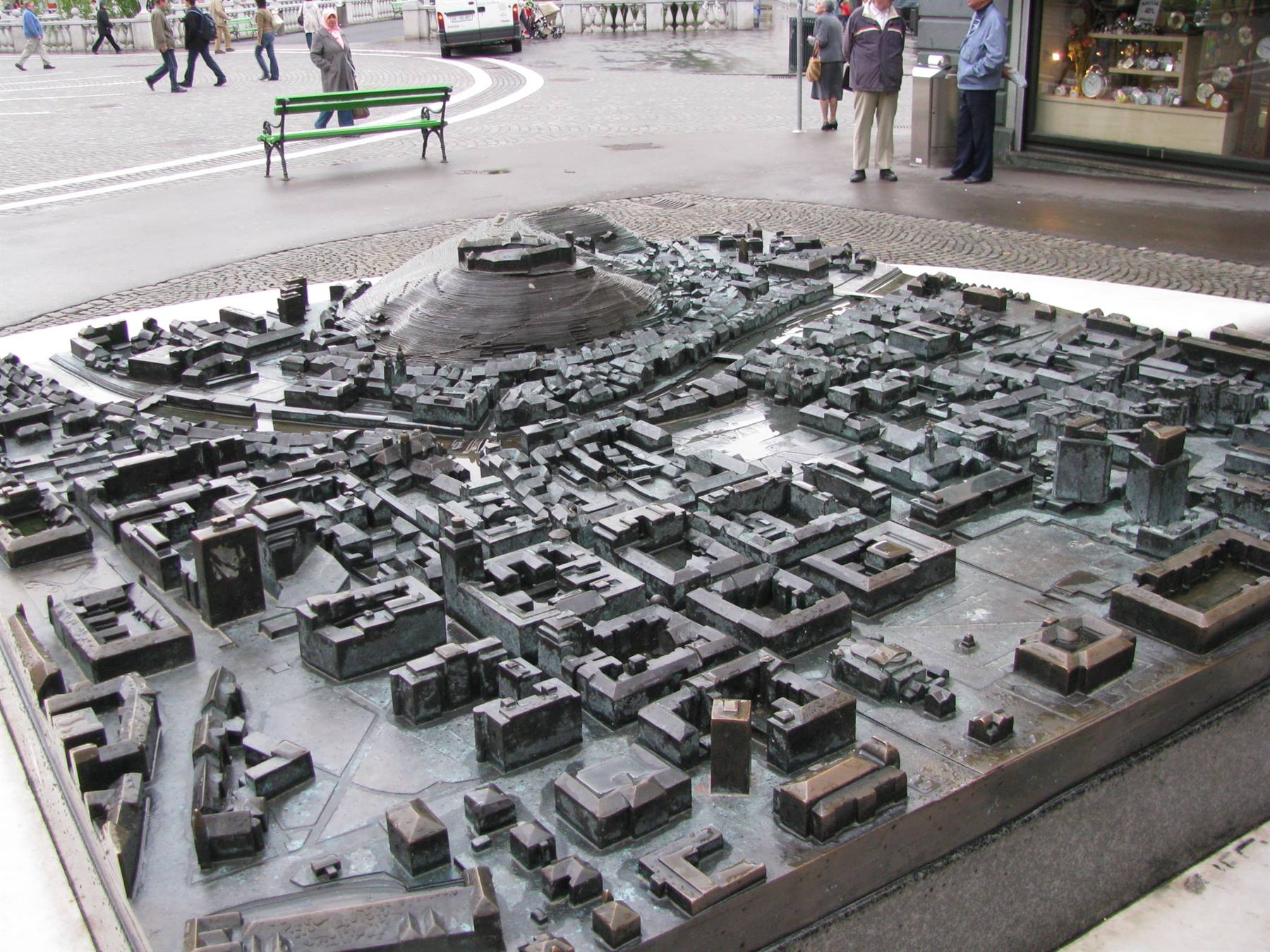 Bronze city model with fortress, tourists standing around the square