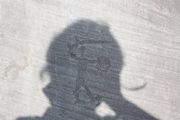 Photographer's shadow over a rock carving of a human figure