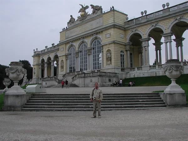 Tourist in front of the Gloriette at Schönbrunn, stone staircase and grey sky