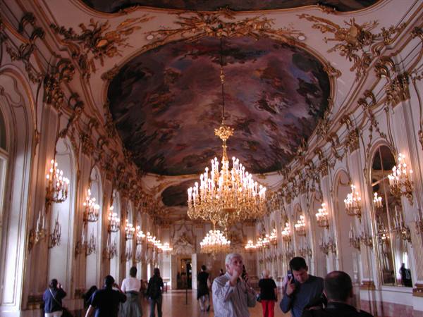 Schönbrunn Grand Gallery, visitors beneath gilded chandeliers and ceiling frescoes