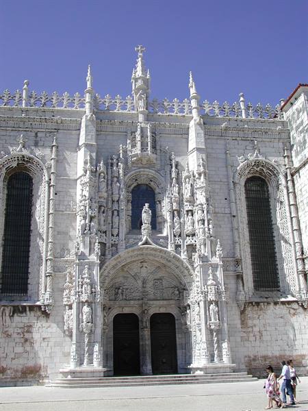 Carved stone facade of the Jerónimos Monastery in Lisbon, tourists walking by