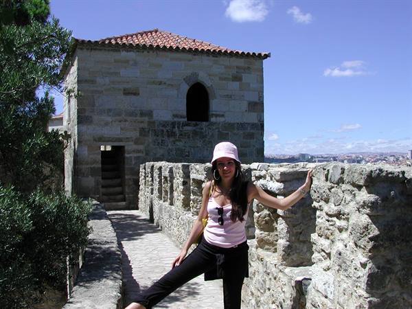 Woman in pink hat beside stone walls and medieval tower, São Jorge Castle