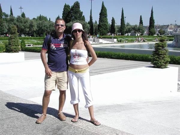 Couple posing on white plaza with lawns and fountains at Praça do Império