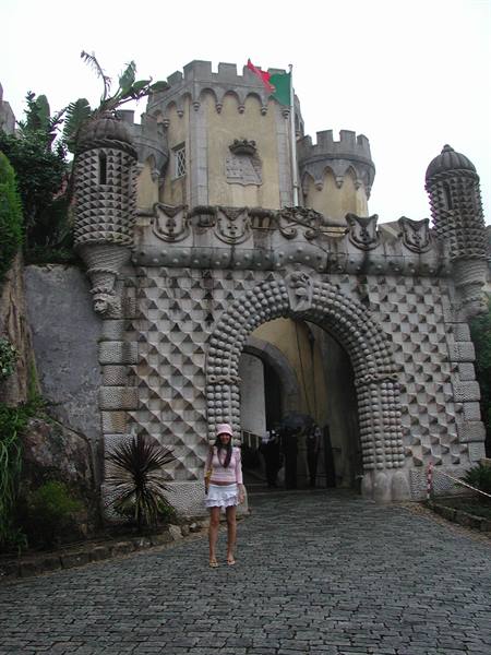 Woman standing before the ornate stone arch of Pena Palace, Sintra