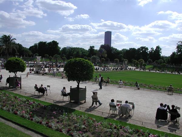 Visitors seated on chairs in the Jardin du Luxembourg, Tour Montparnasse behind