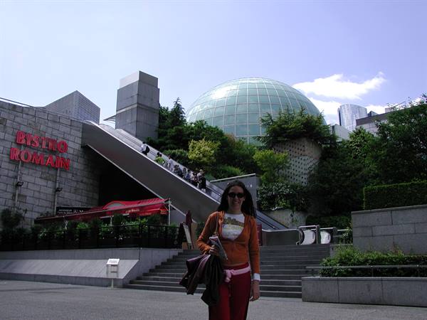 Tourist in front of the glass globe and escalators of Les Quatre Temps, La Défense
