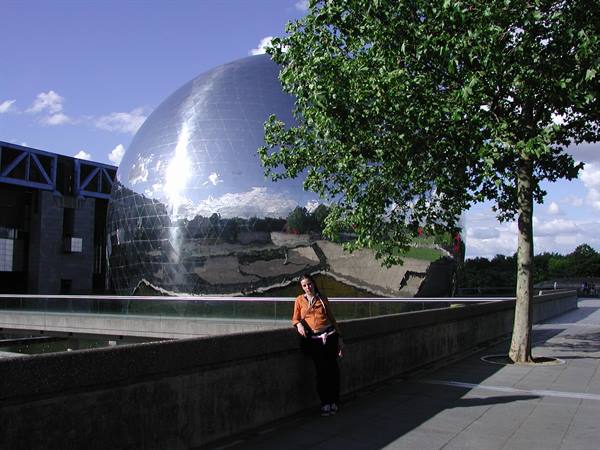 Woman leaning on a wall in front of the mirrored Géode, Parc de la Villette, Paris