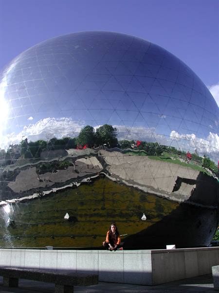 Woman crouching in front of the mirrored sphere at Parc de la Villette, Paris