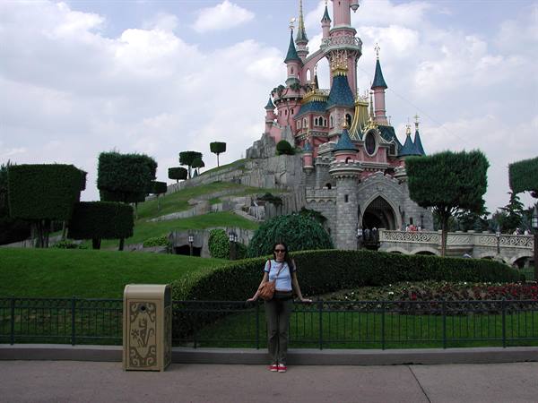 Smiling tourist posing in front of the Sleeping Beauty Castle at Disneyland Paris