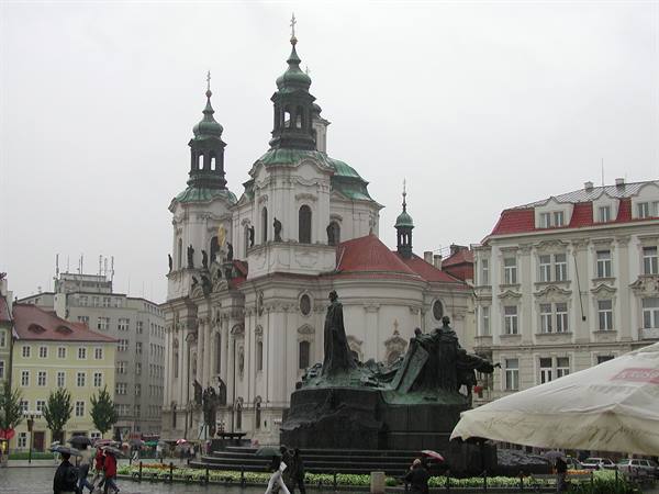 Old Town Square in Prague, Jan Hus memorial in front of St Nicholas Church, tourists with umbrellas