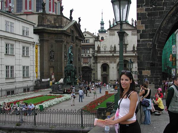 Smiling tourist with map near Charles Bridge, baroque churches and flowerbeds
