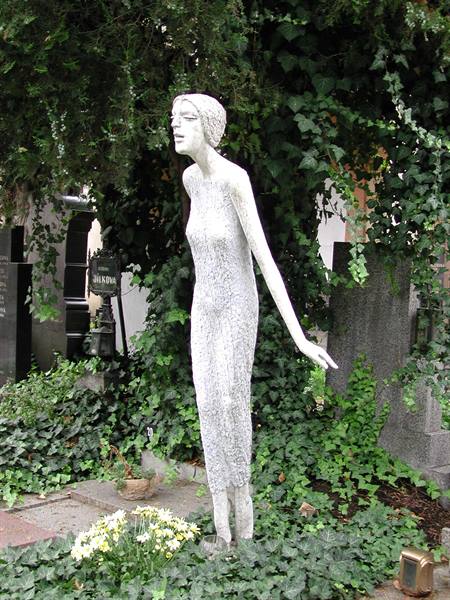 Stone statue of a woman among ivy and gravestones in a cemetery