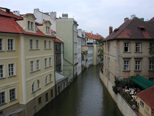 Čertovka canal in Prague, colorful houses with red roofs, café terrace below