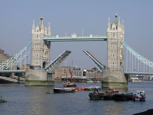 Tower Bridge raised over the Thames, moored boats waiting beneath the twin towers
