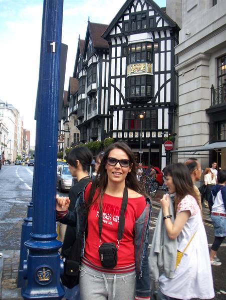 Woman in sunglasses beside Tudor-style timber building in London
