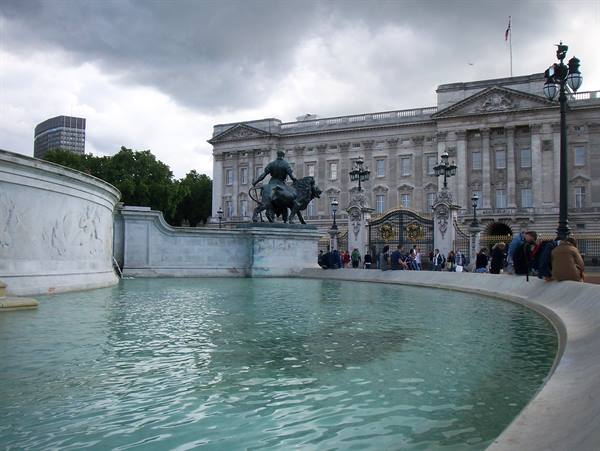 Victoria Memorial fountain before Buckingham Palace, cloudy sky, tourists near the gates