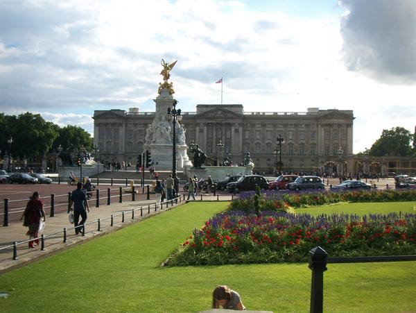 Buckingham Palace with the Victoria Memorial and flowerbeds under a cloudy sky