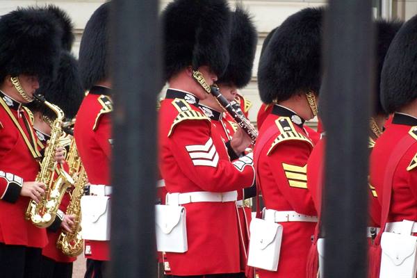 Royal guards in red tunics and black bearskin caps playing saxophones in London