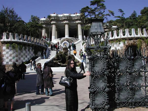 Tourist touching Gaudí's wrought iron gate at Park Güell, Barcelona