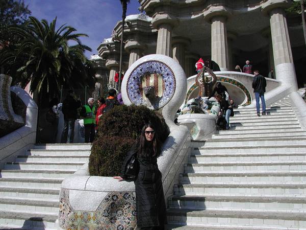Woman posing on mosaic-covered staircase at Park Güell, Barcelona