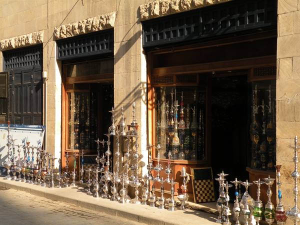 Silver hookahs displayed outside a stone shopfront in morning light