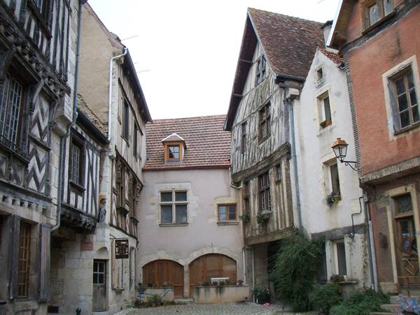 Medieval half-timbered houses on cobblestone square, aged wood and brickwork