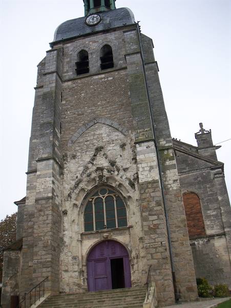 Grey stone church tower with clock and purple portal, overcast sky