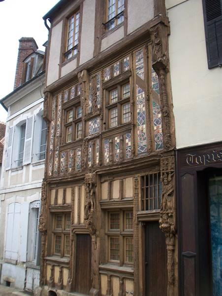 Old half-timbered house with carved wooden facade among street buildings
