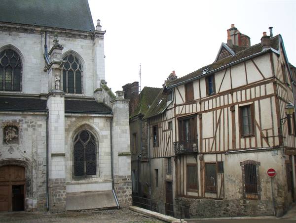 Half-timbered wooden houses beside a stone church under a grey sky