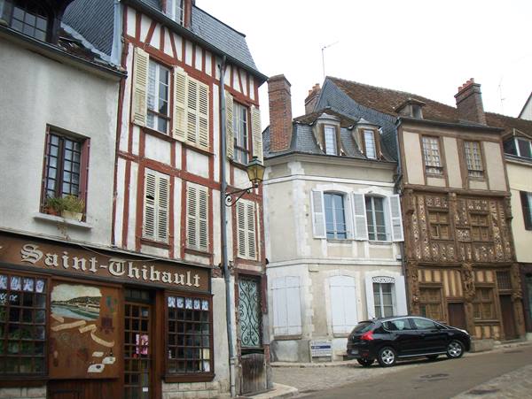 Half-timbered houses on Auxerre streets, a parked car near the Saint-Thibault shop
