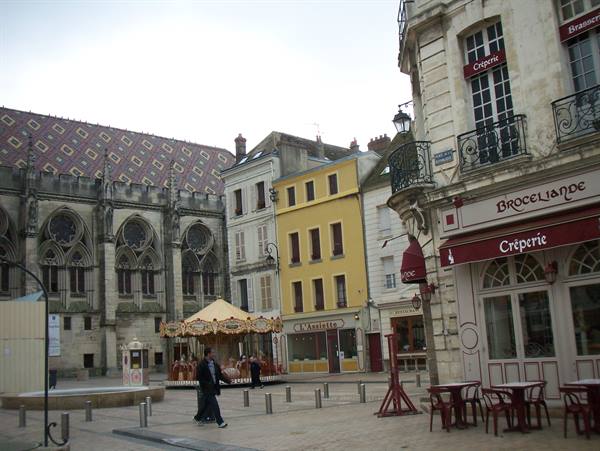 Carousel and Gothic church beside a crêperie in the square