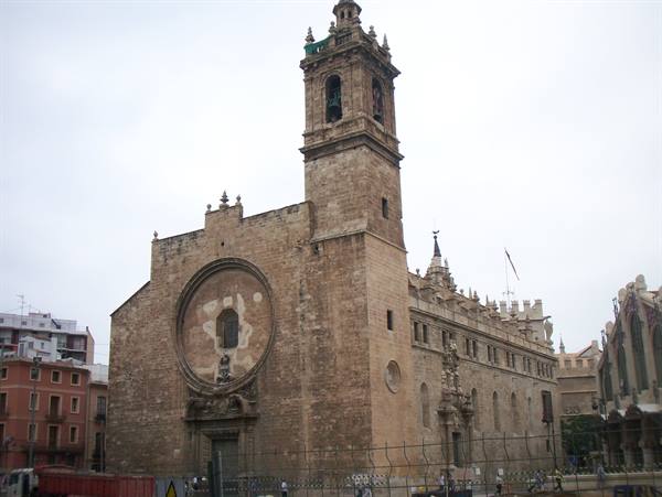 Gothic stone church with rose window and bell tower under grey sky