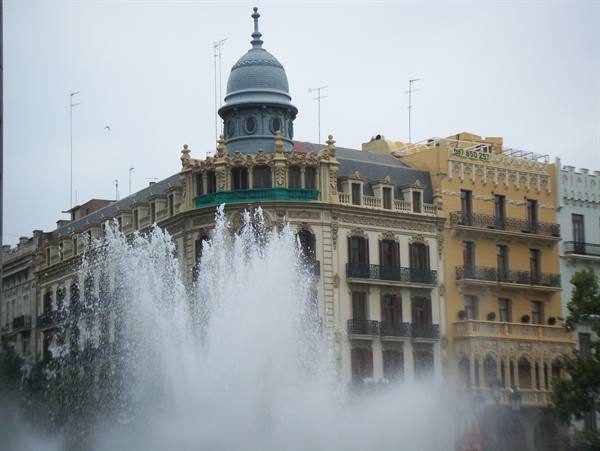 Fountain spraying water in front of Art Nouveau buildings in Valencia