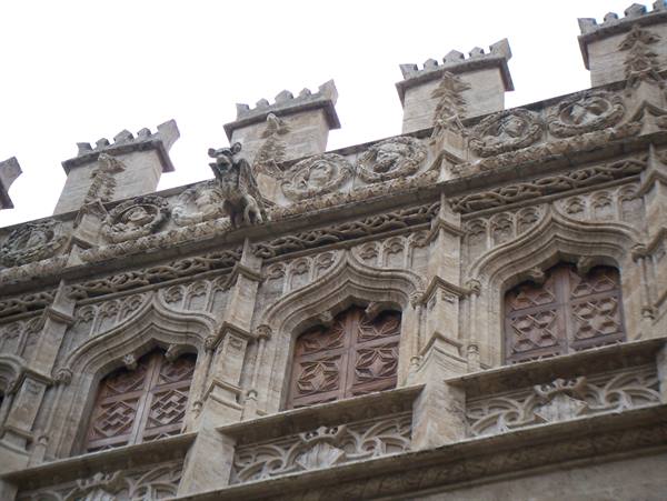 Gothic stone facade with carved windows and a gargoyle