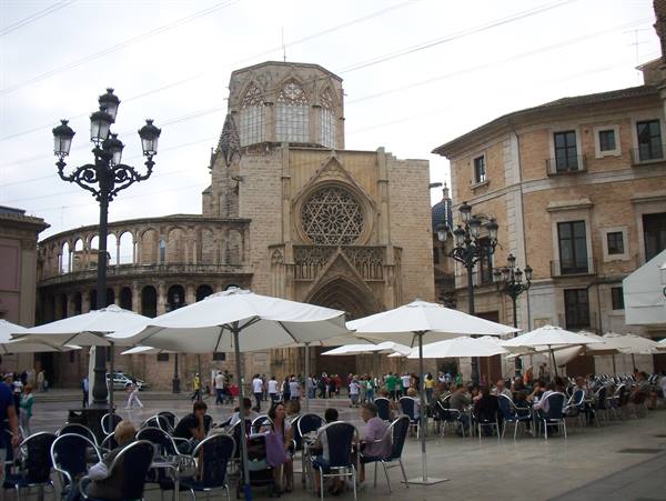 Café umbrellas before Valencia Cathedral's gothic stone façade and rose window