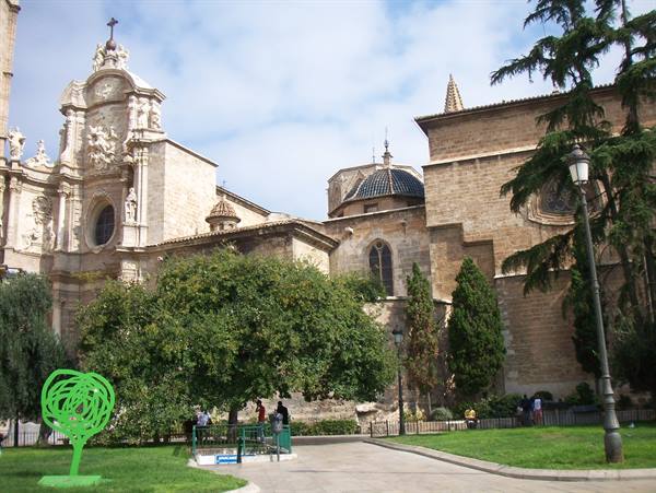 Valencia Cathedral: baroque stone facade, tiled dome, tourists strolling beneath trees