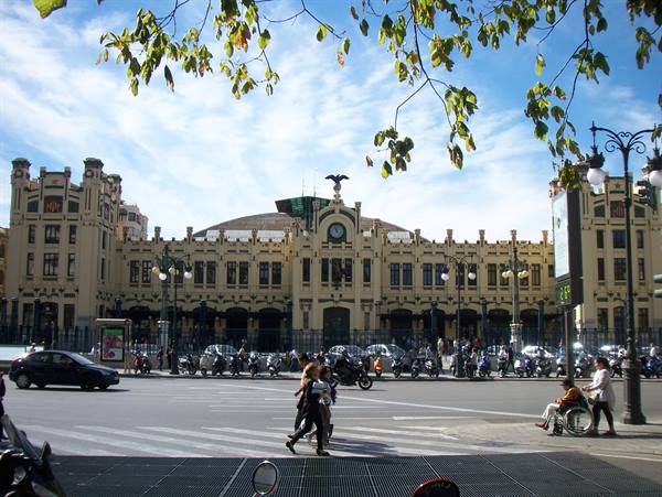 Pedestrians cross the street in front of Valencia's Estación del Norte facade