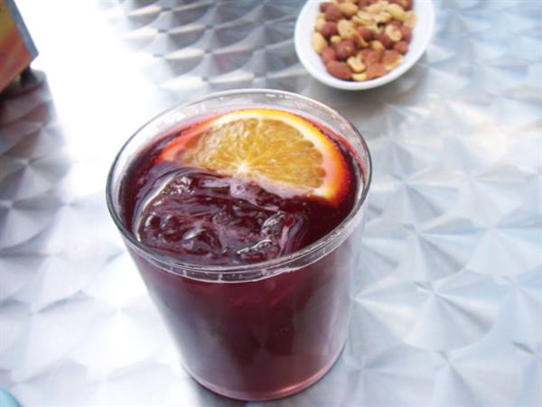 Glass of tinto de verano with orange slice and ice, bowl of almonds nearby