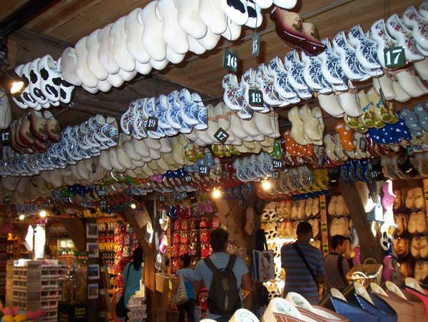 Tourists beneath ceilings of painted wooden clogs hanging in a souvenir shop