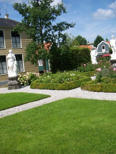 White marble statues among hedges and roses in a wooden house garden