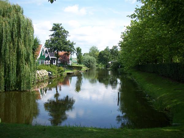 Green houses with red roofs along a still canal at Zaanse Schans